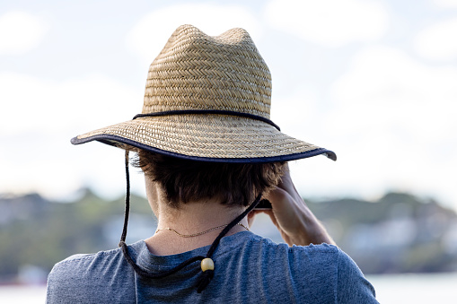 Rear view of 26 years old man with straw hat taking photos, outdoor, background with copy space, full frame horizontal composition