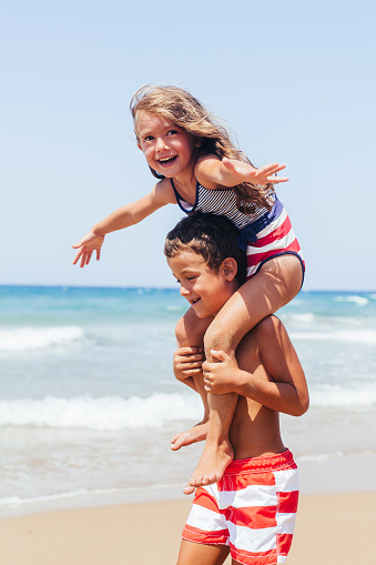 Children having fun carrying on shoulder on the beach on their summer vacation