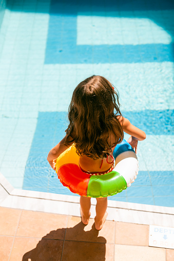 Rear view of little girl preparing to enter in the swimming pool