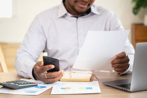 istock African black businessmen sit on mobile phones communicating with clients and making financial reports and studying annual profit analysis. An accountant checks the financial status of the company. 1483383049