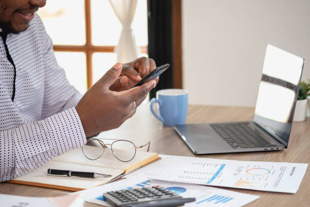 istock African black businessmen sit on mobile phones communicating with clients and making financial reports and studying annual profit analysis. An accountant checks the financial status of the company. 1483383115