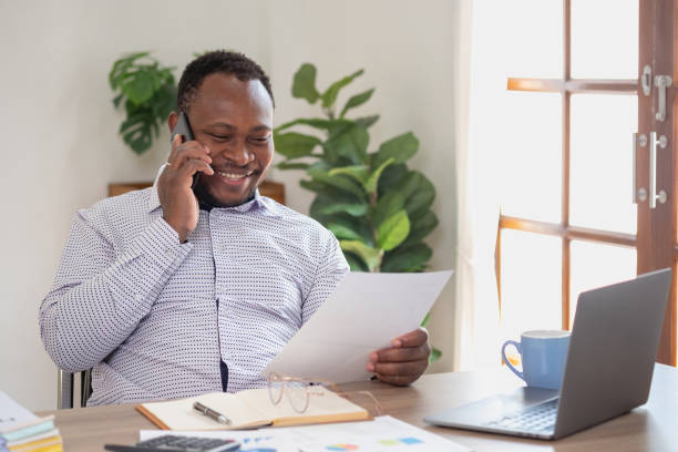 istock African black businessmen sit on mobile phones communicating with clients and making financial reports and studying annual profit analysis. An accountant checks the financial status of the company. 1483383154