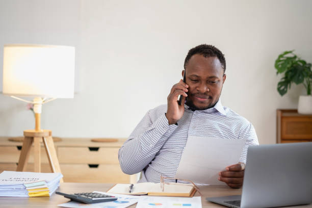istock African black businessmen sit on mobile phones communicating with clients and making financial reports and studying annual profit analysis. An accountant checks the financial status of the company. 1483383358
