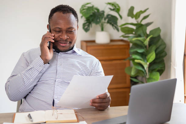 istock African black businessmen sit on mobile phones communicating with clients and making financial reports and studying annual profit analysis. An accountant checks the financial status of the company. 1483384122