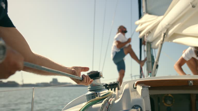 Boat, sailing and men working with rope on winch for travel, adventure or journey at sea with crew hands. Friends or people together to work on sailboat rig for transportation and freedom on ocean