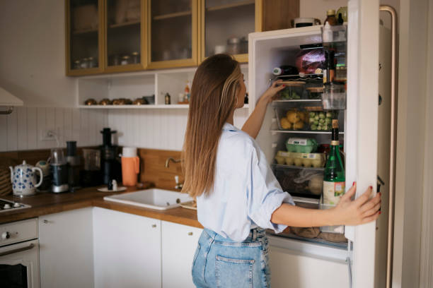 istock Young woman looking for food inside a fridge in kitchen 1483385632