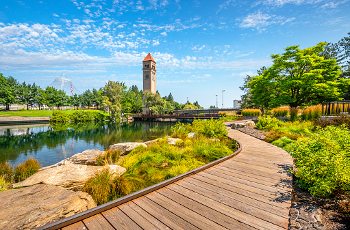 View from the Spokane River waterfront promenade path looking towards the expo pavilion and clock tower at the public Riverfront Park in downtown Spokane, Washington, USA.