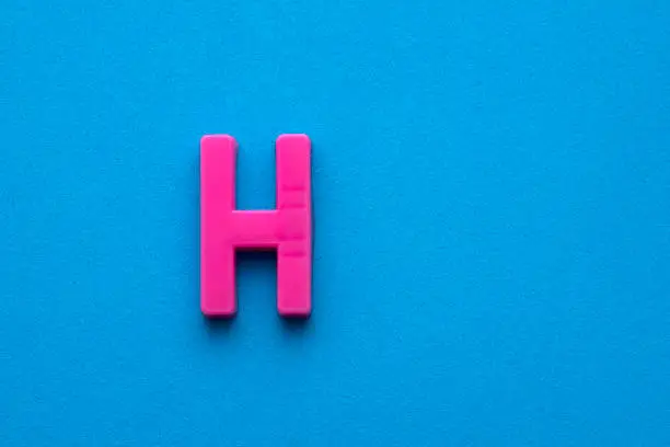 Alphabet letter H - Pink plastic piece on blue foamy background