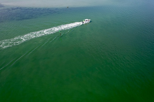 Beautiful drone photography of Honeymoon Island's green waters and sand bars and the speed boat in the distance.