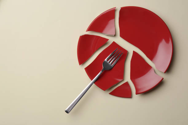 istock Pieces of broken red ceramic plate and fork on beige background, top view. Space for text 1483390181