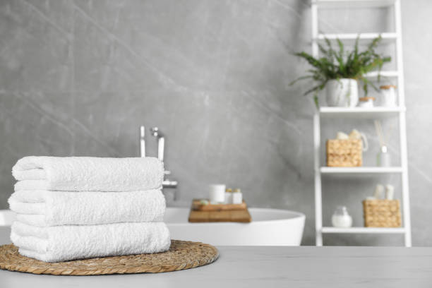 istock Stacked bath towels on light table in bathroom. Space for text 1483390766