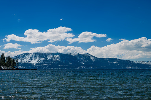 Wide winter view of Lake Tahoe looking west, with snow covered mountains in background.\n\nTaken from Zephyr Cove, Lake Tahoe, California, USA  looking west.