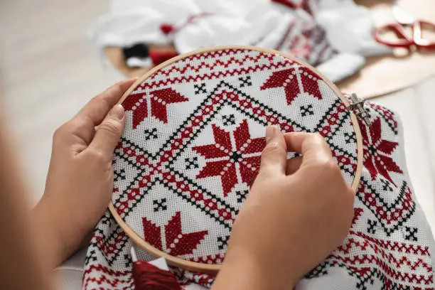 Woman embroidering white shirt with colorful threads in hoop, closeup. Ukrainian national clothes