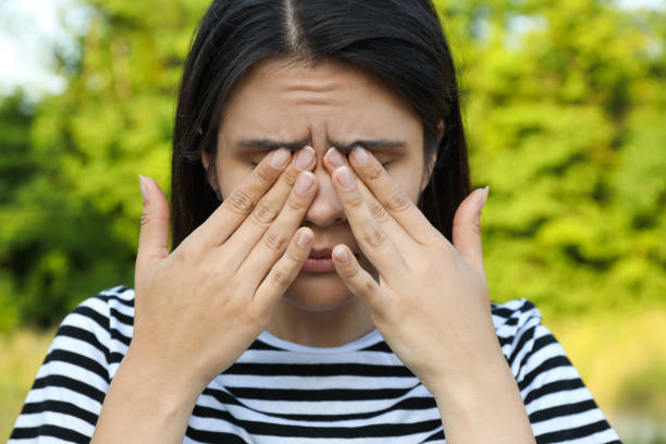 Young woman suffering from eyestrain outdoors on sunny day Young woman suffering from eyestrain outdoors on sunny day human eye scratching allergy rubbing stock pictures, royalty-free photos & images