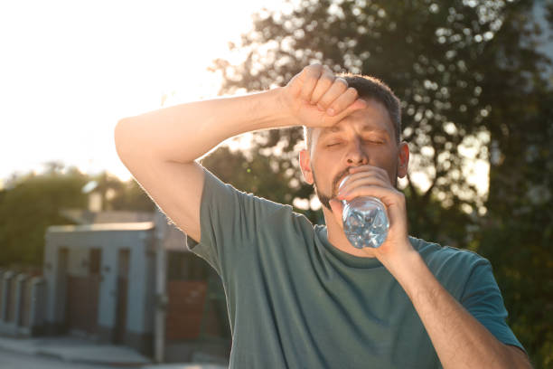 istock Man drinking water outdoors on hot summer day. Refreshing drink 1483392746