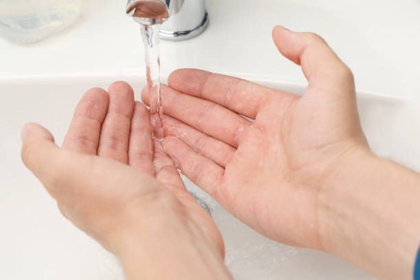 istock Man using water tap to wash hands in bathroom, closeup 1483392755