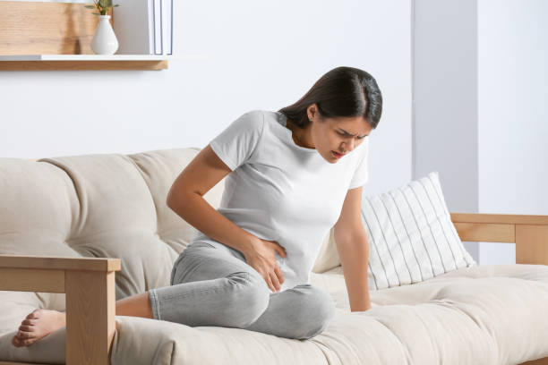 Young woman suffering from menstrual pain on sofa at home Young woman suffering from menstrual pain on sofa at home Endometriosis stock pictures, royalty-free photos & images
