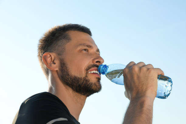 istock Happy man drinking water against blue sky on hot summer day. Refreshing drink 1483392785