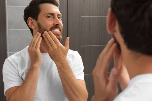 istock Smiling bearded man looking at mirror in bathroom 1483392788