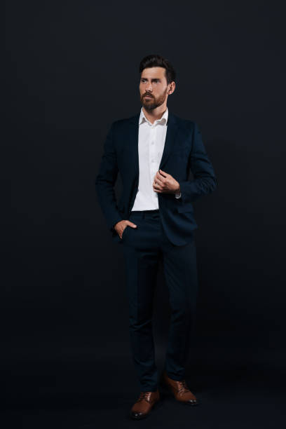 istock Handsome bearded man in suit looking away on black background 1483392911