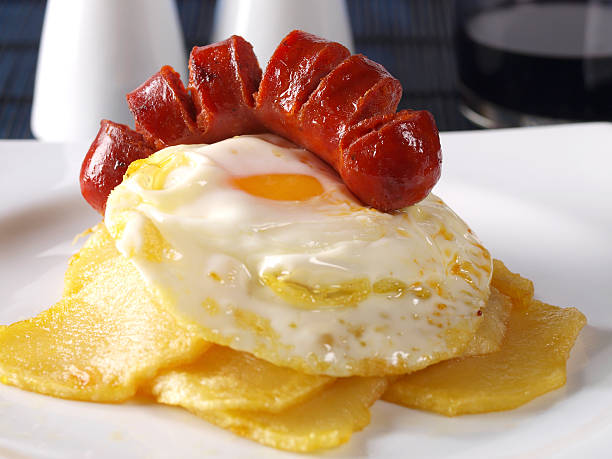 Fried eggs & potatoes with “chorizo” (red spicy sausage) stock photo