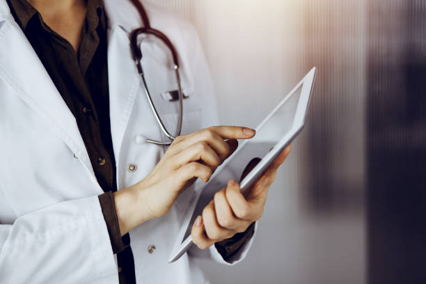 istock Unknown female doctor using tablet computer in sunny clinic. Medicine concept 1483407711