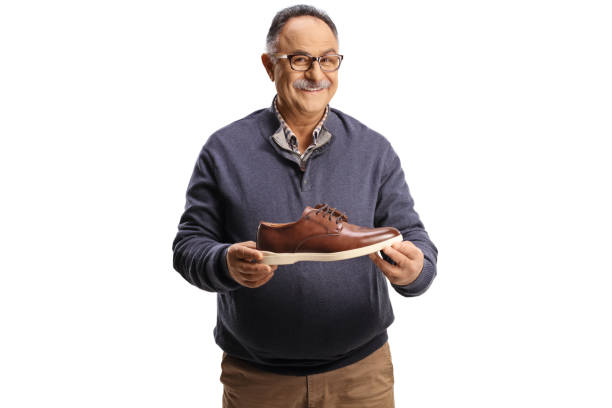 Happy mature man holding a brown leather shoe isolated on white background