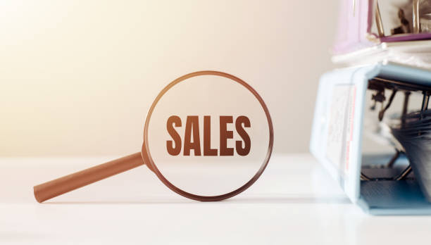 magnifying glass with the word sales on office table. - sale stok fotoğraflar ve resimler