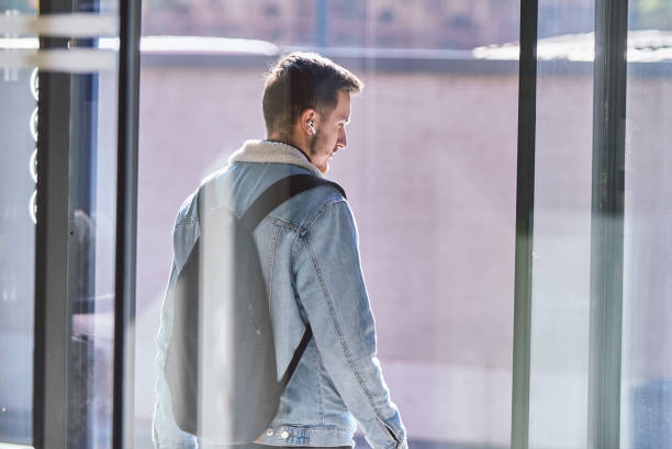 istock After finishing his work, a man steps out of his office while carrying a backpack and wearing wireless headphones, ready to unwind and enjoy the freedom of the urban environment, suggesting a modern approach to work and personal life. 1483420258