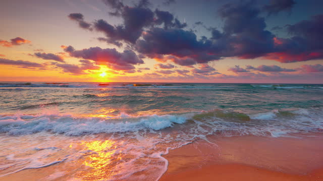 Tropical beach sunrise with golden sun rays over the sand and sea