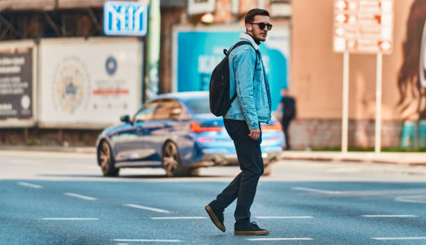 istock Student walks through the city wearing sunglasses, carrying a backpack, and using wireless headphones, embodying the modern urban lifestyle and the ability to stay connected while on-the-go. 1483421024