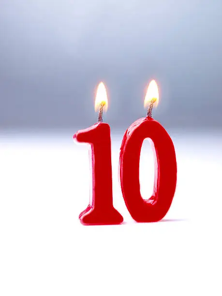 Birthday-anniversary candle with Nr. 10. Graduated grey background.