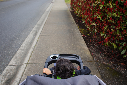 Toddler sits in a stroller on a sidewalk