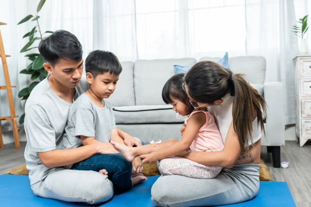 genitori asiatici, figlia figlio, famiglia adorabile, quattro di loro che fanno attività insieme, con meditazione, tre di loro sedevano con gli occhi chiusi, ma la figlia maliziosa saliva in braccio alla madre. - torso physical therapy patient relaxation exercise foto e immagini stock