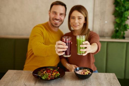 Mid adult couple enjoy eating salads and drinking smoothies in salad bar