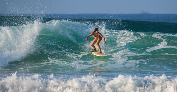 A young native Hawaii man surfing on the wave of Poipu Beach, on the island of Kauai, Hawaii, USA. He is on a pink surfboard and making a turn on the wave in the aqua sea of Kauai. Photographed in horizontal format with copy space available.