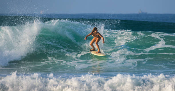 piękna utalentowana młoda surferka w bikini jadąca rano na zielonej fali, tropikalny klimat plaży. - co surfing zdjęcia i obrazy z banku zdjęć