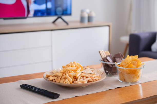 istock Snack on wooden table with television on background 1483448707