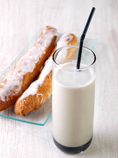 Tall glass of milk with two pieces of bread over wood table stock photo