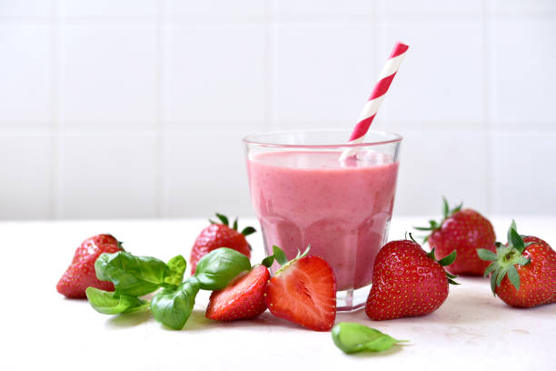 Fresh banana strawberry smoothie with basil in a glass. stock photo