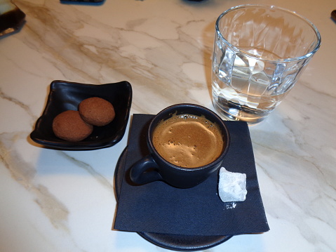 A cup of Greek coffee with locum candy, cookies and a glass of water