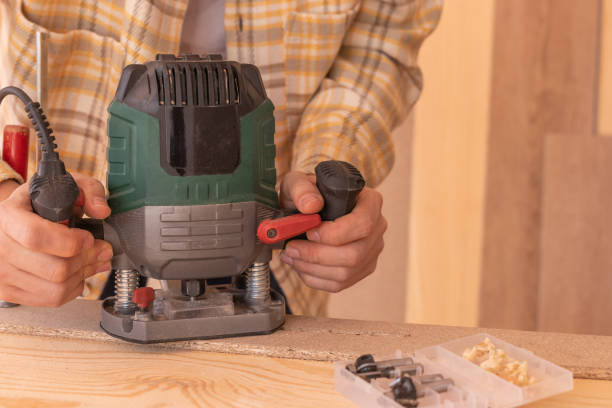 istock Crop anonymous male carpenter using electric milling machine while cutting wood plank in home workshop 1483467504