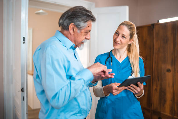 istock Cheerful Caucasian Nurse At Patients Home Using Digital Tablet 1483467709