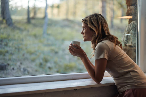 istock Pensive woman looking through window during coffee time at home. 1483470363