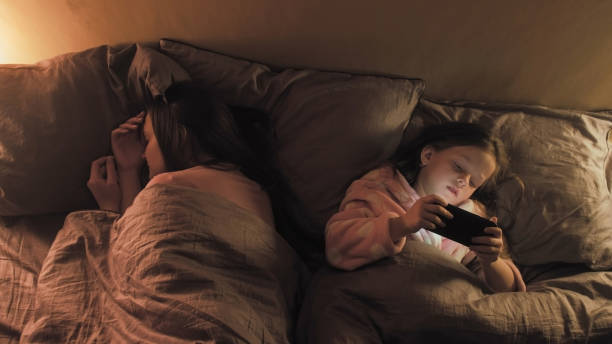 istock Kid insomnia gadget night girl phone sleeping mom 1483472155