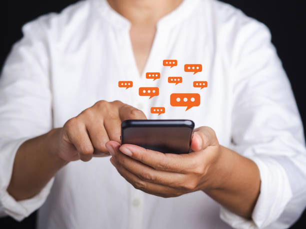 istock Businesswoman using a smartphone with a conversation icon while standing on a gray background. 1483472960