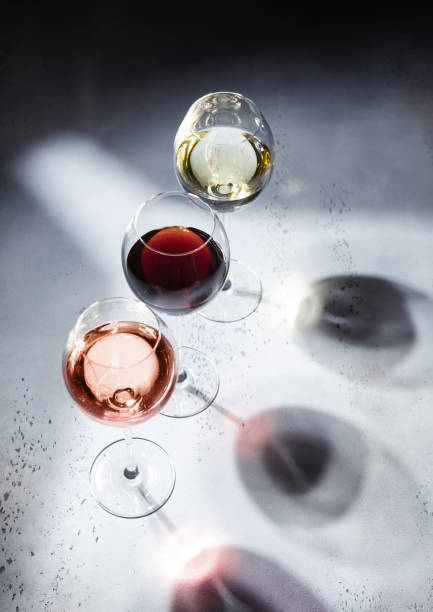 istock Pink rose,red and white wine glasses on light background with shadows. 1483478366