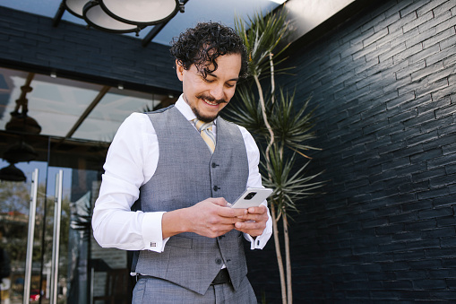 young latin businessman holding mobile phone and texting message in Mexico city Latin America, hispanic business people