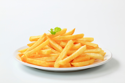 hamburger, tomato sauce, and French fries in a paper bag on a white plate. Isolated on a white background. Top view