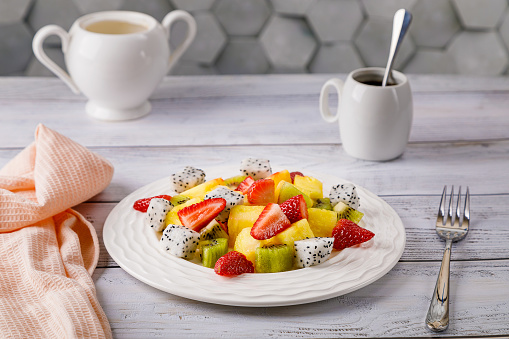 Fruit salad of pineapple, strawberries, kiwi and pitahaya in a white plate. High quality photo